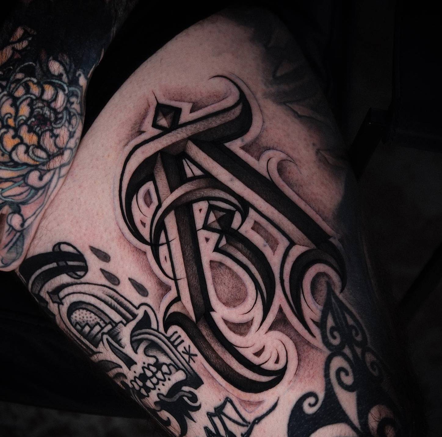 Arm tattoo of a woman with red decorative elements in her hair and black calligraphic designs